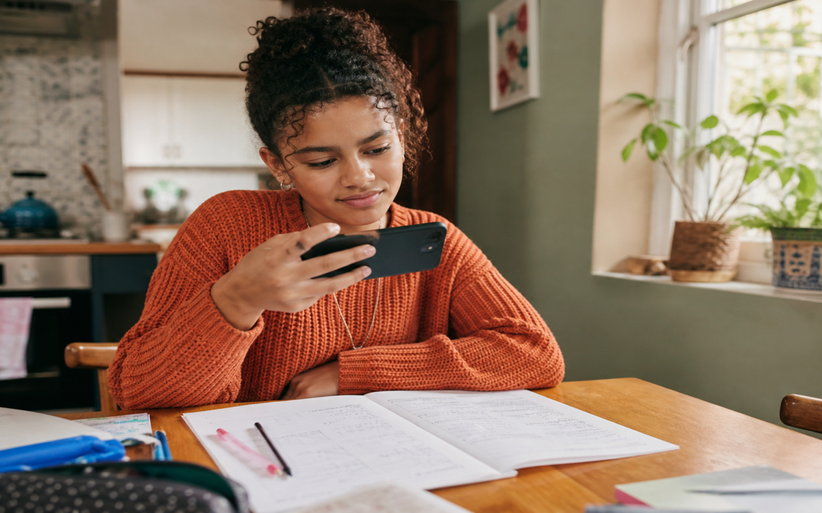 Coloured South African learner photographing homework with smartphone